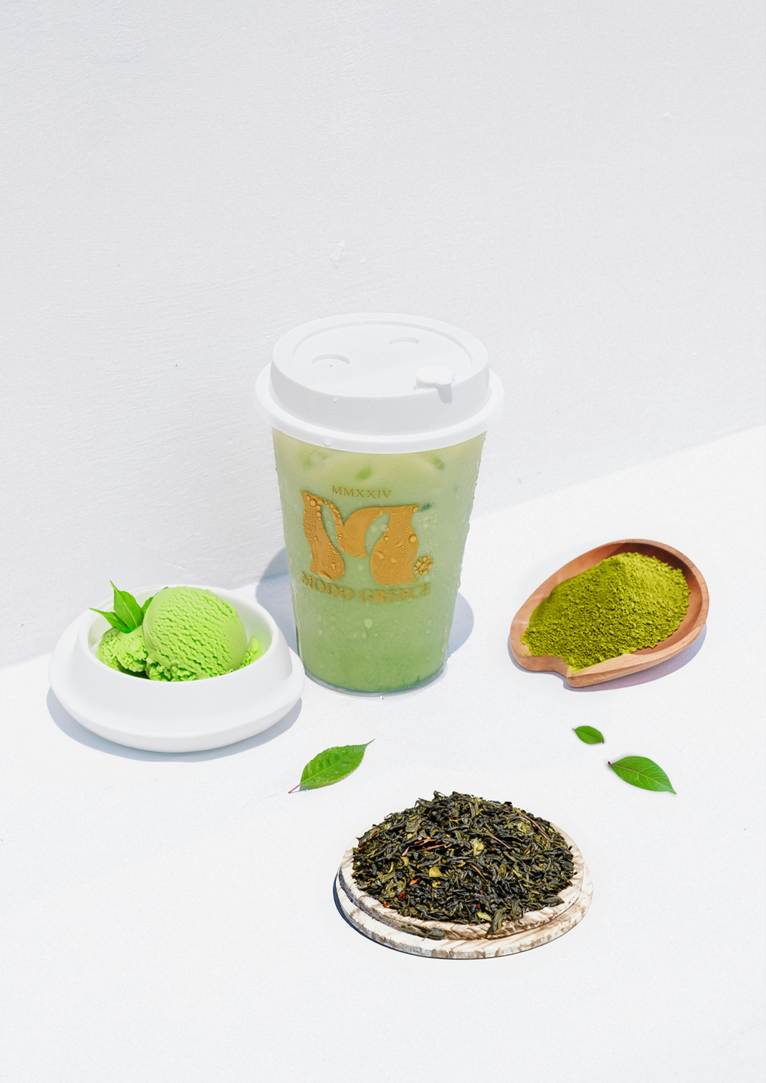 A cup of green tea next to a spoon of green tea