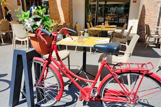 a red bicycle parked next to a yellow table