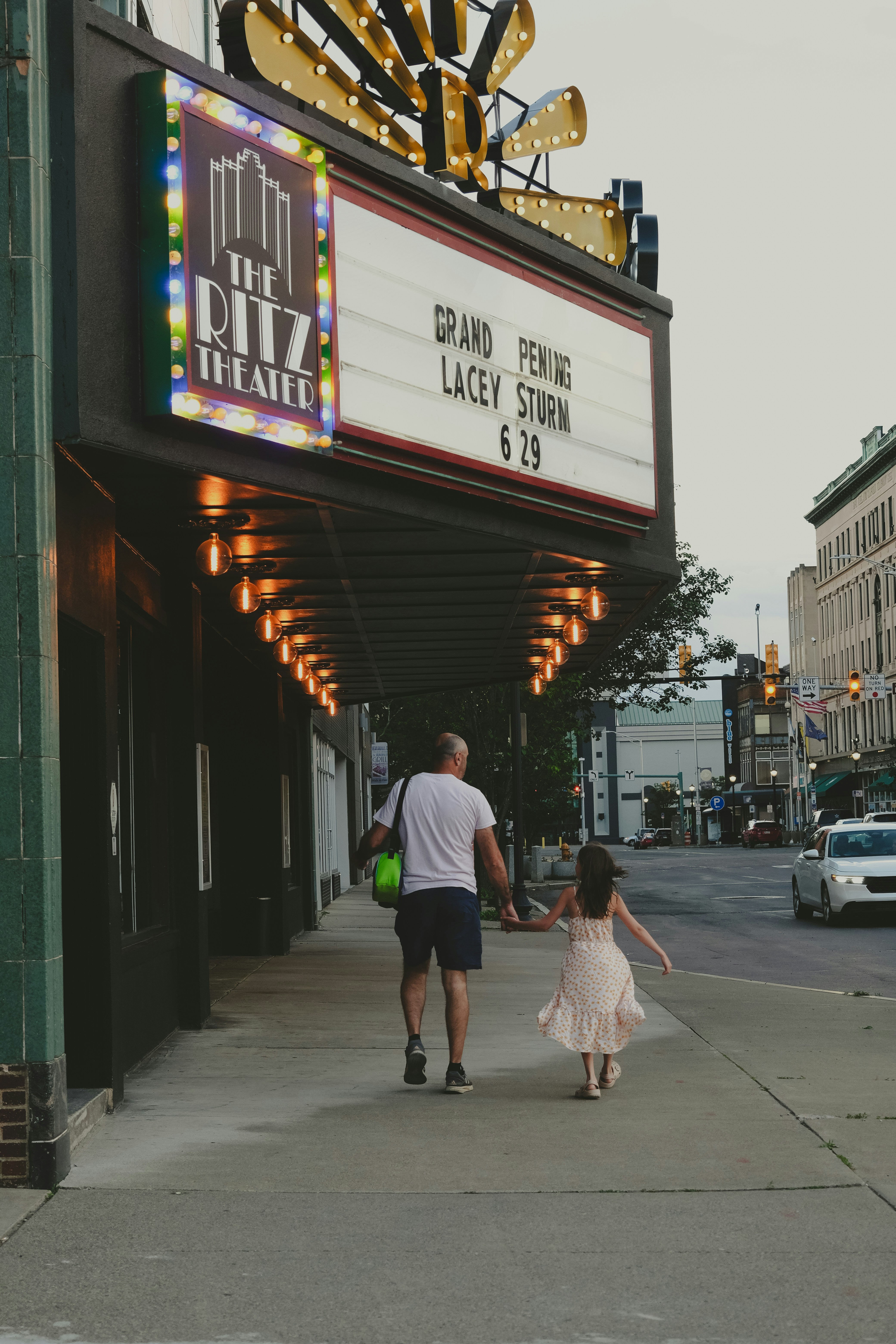 a man and a little girl walking down a sidewalk