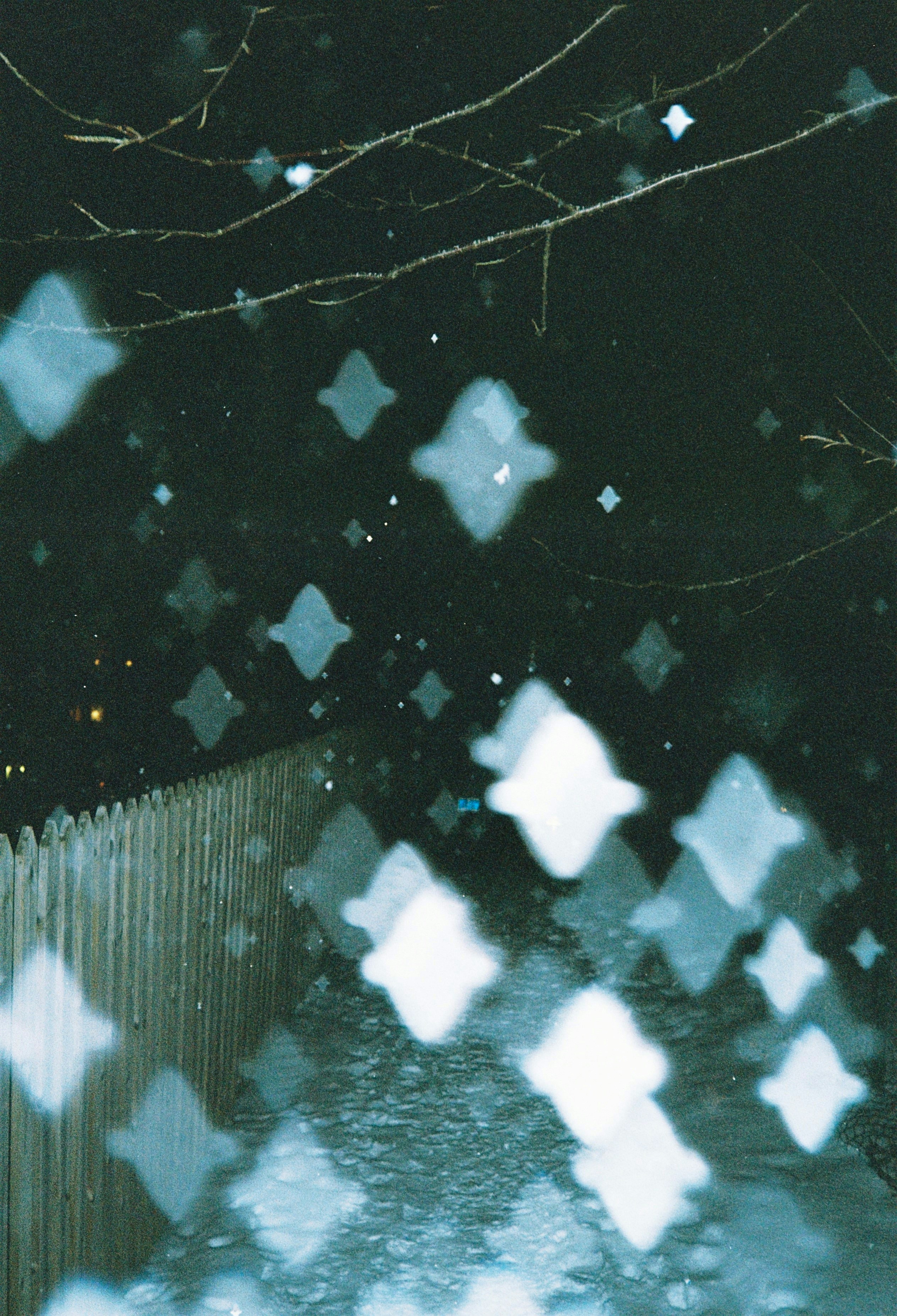 a blurry photo of a fence and a street at night