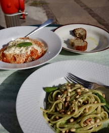 a plate of pasta and a plate of bread on a table