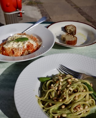 a plate of pasta and a plate of bread on a table