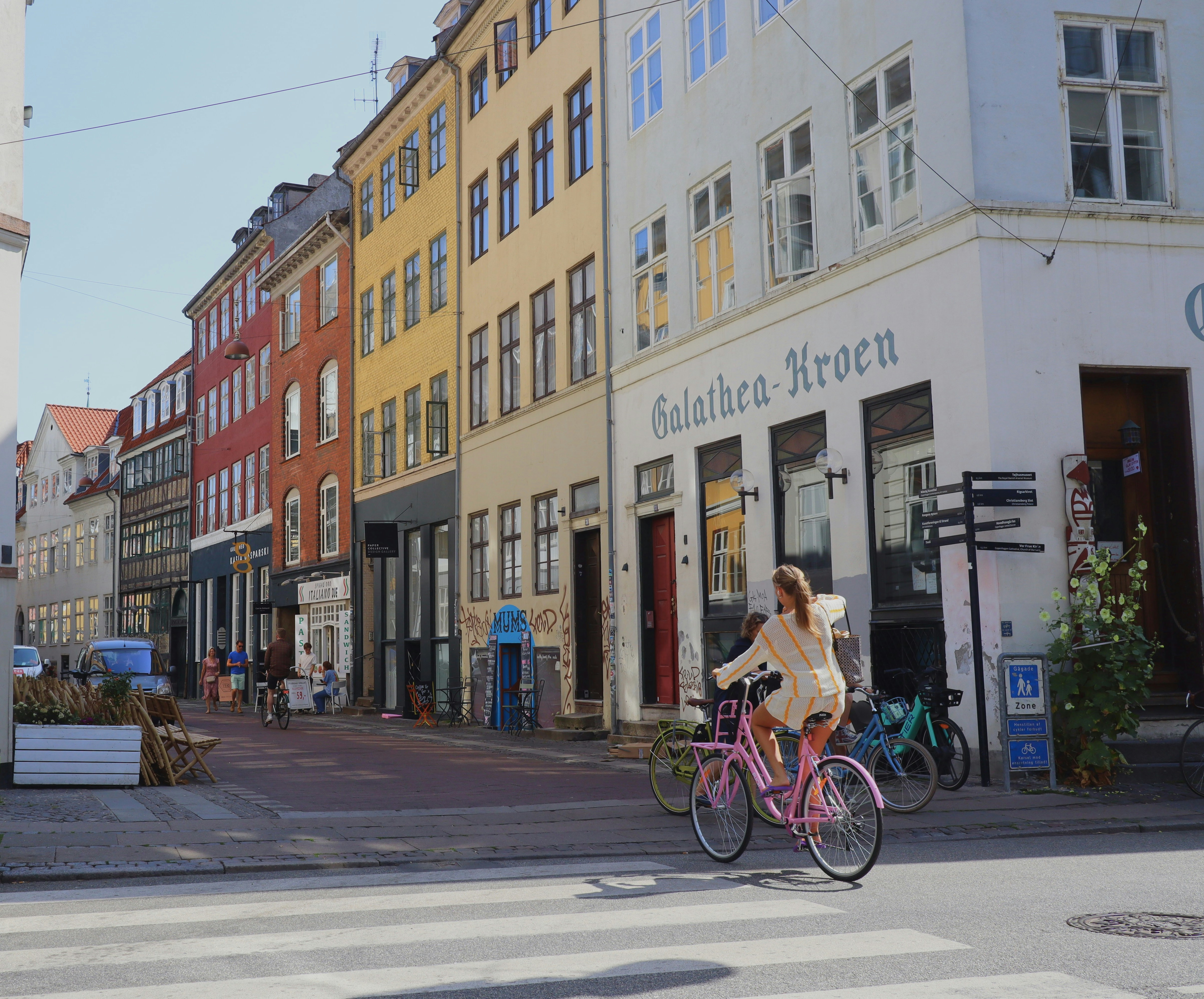 a woman riding a bike down a street next to tall buildings, 
