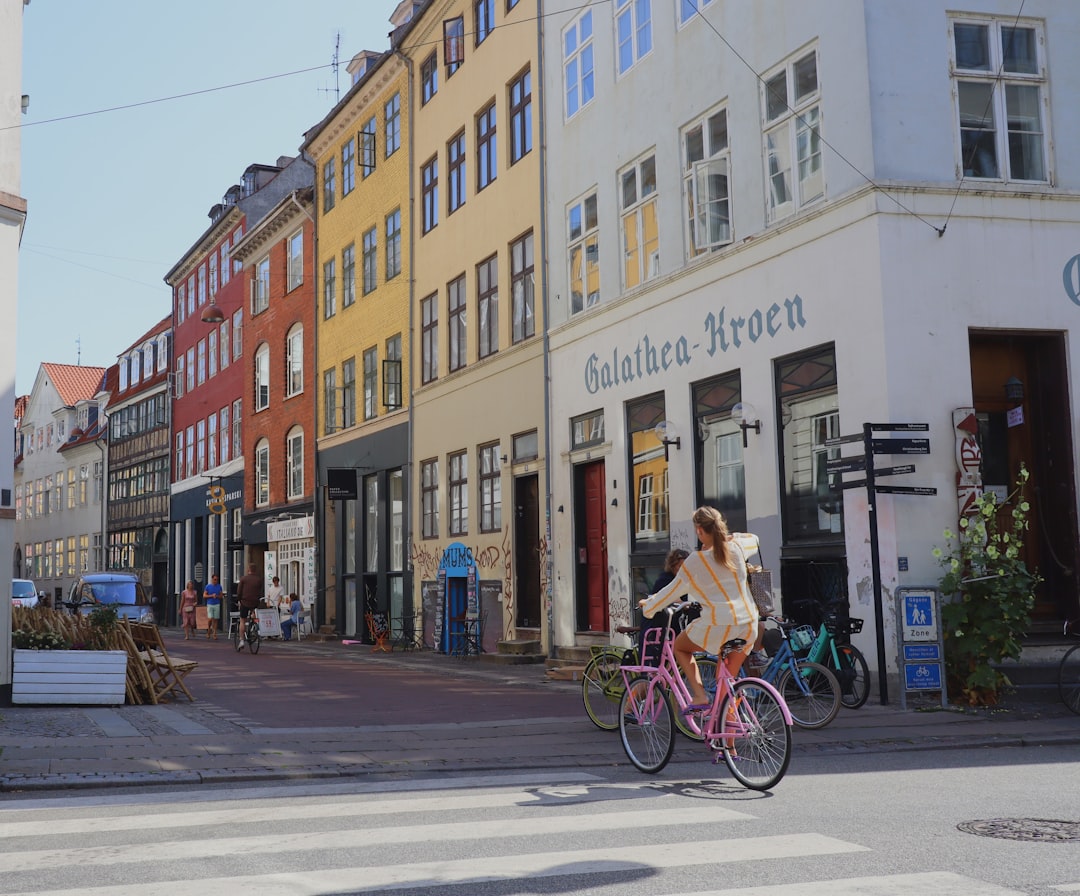 a woman riding a bike down a street next to tall buildings,