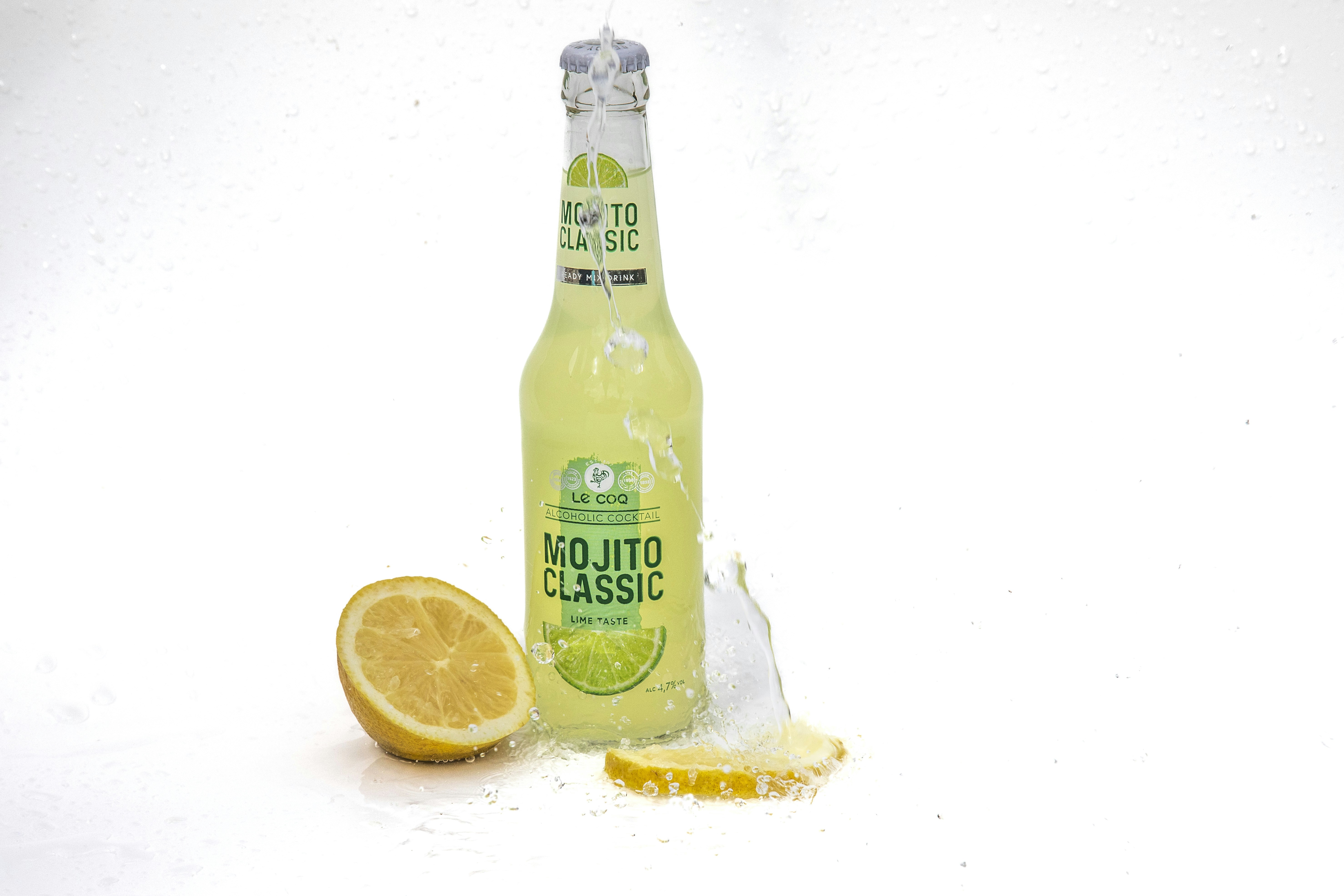 sebotol mojito klasik di sebelah setengah lemon