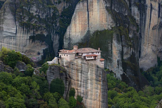 a house on top of a cliff in the mountains