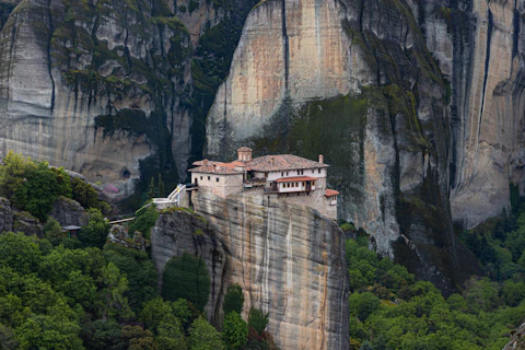 a house on top of a cliff in the mountains