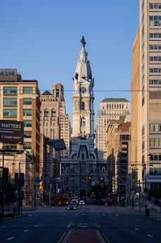 a city street with tall buildings and a clock tower