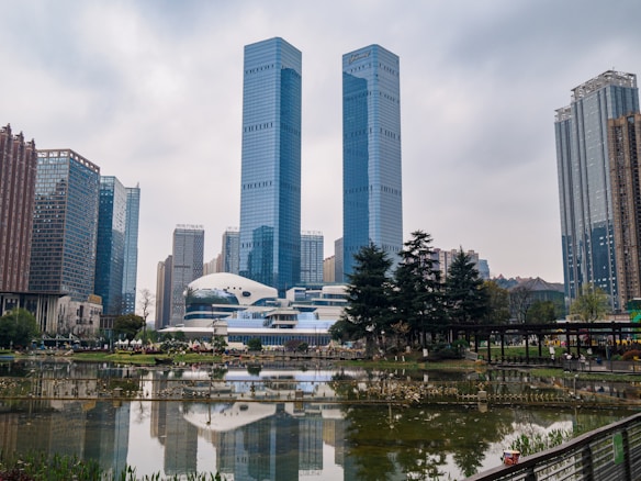 a city with tall buildings and a pond in front of it