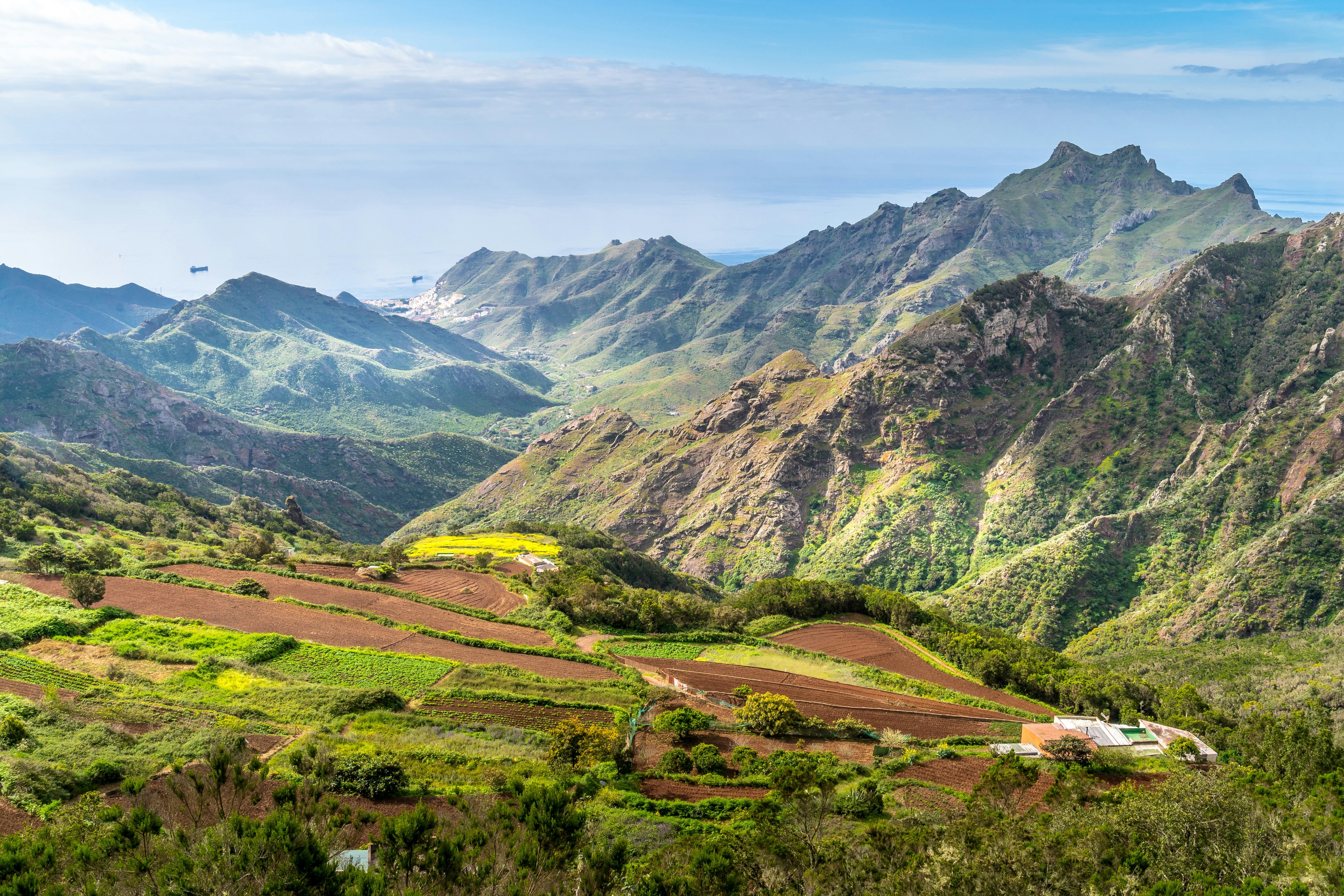 a scenic view of a mountain range with a house in the foreground