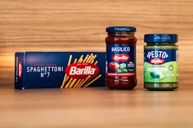 two jars of pasta sauce next to a box of pasta sauce