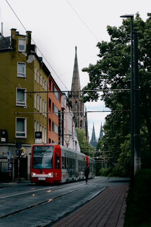 a red train traveling down a street next to tall buildings