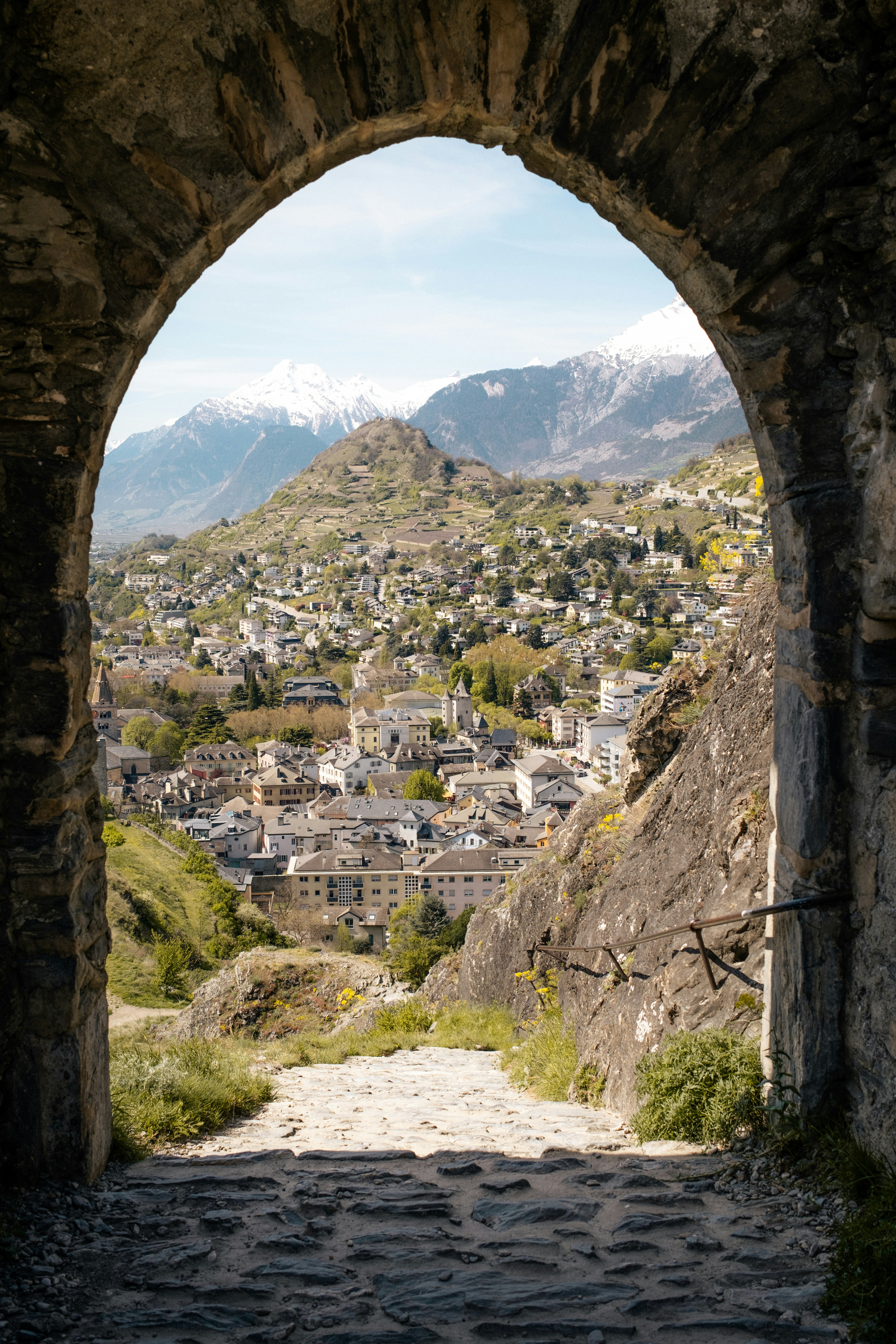 a stone arch with a view of a town below