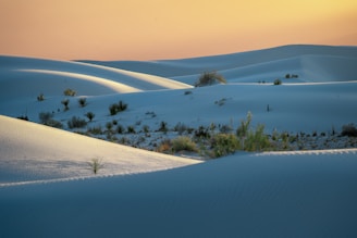 the sun is setting over a vast expanse of sand dunes
