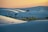 the sun is setting over a vast expanse of sand dunes