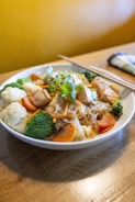 a bowl of food with chopsticks on a table