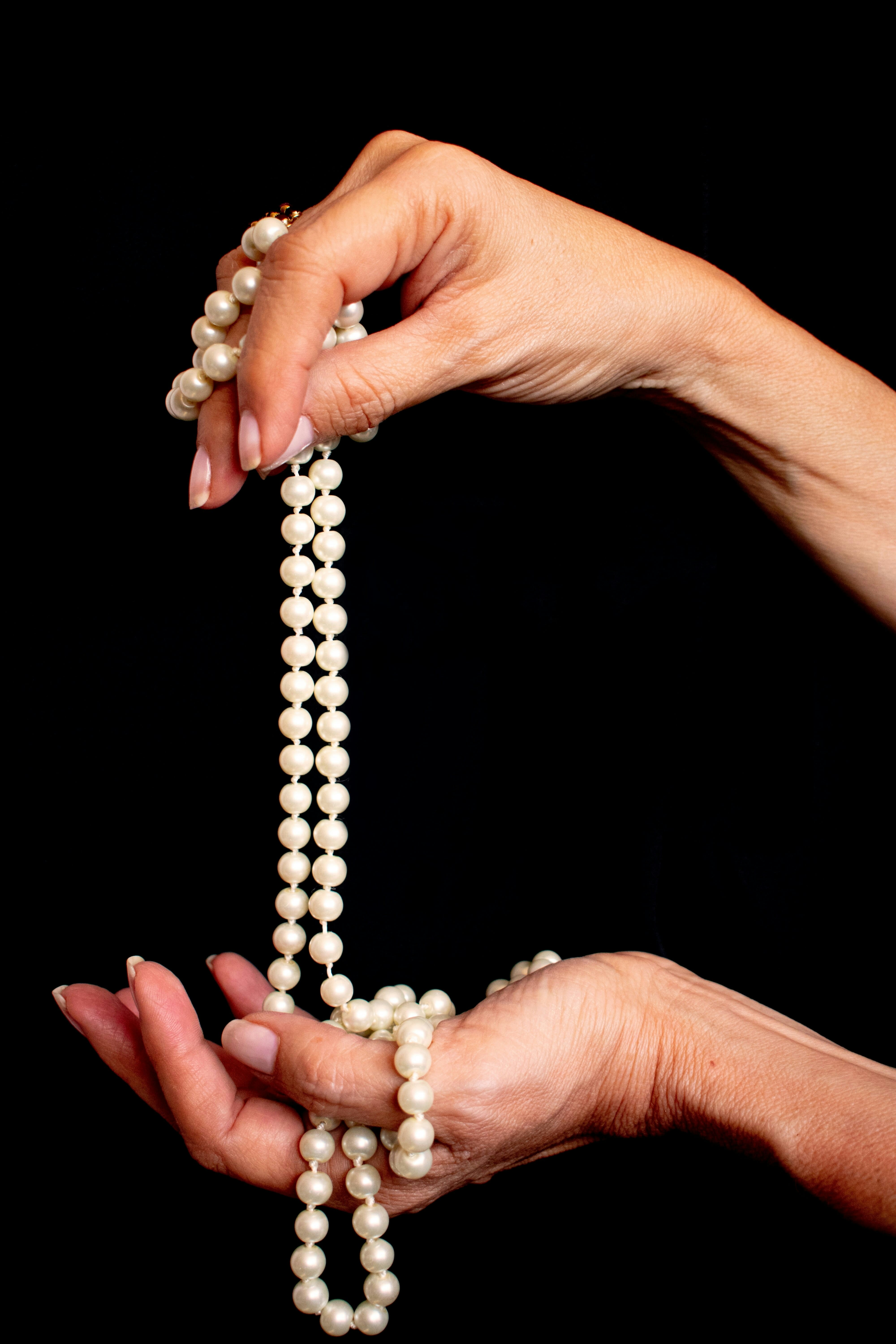 a woman holding a strand of pearls in her hands