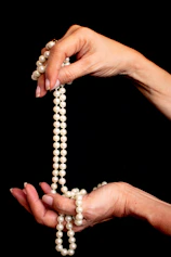 a woman holding a strand of pearls in her hands