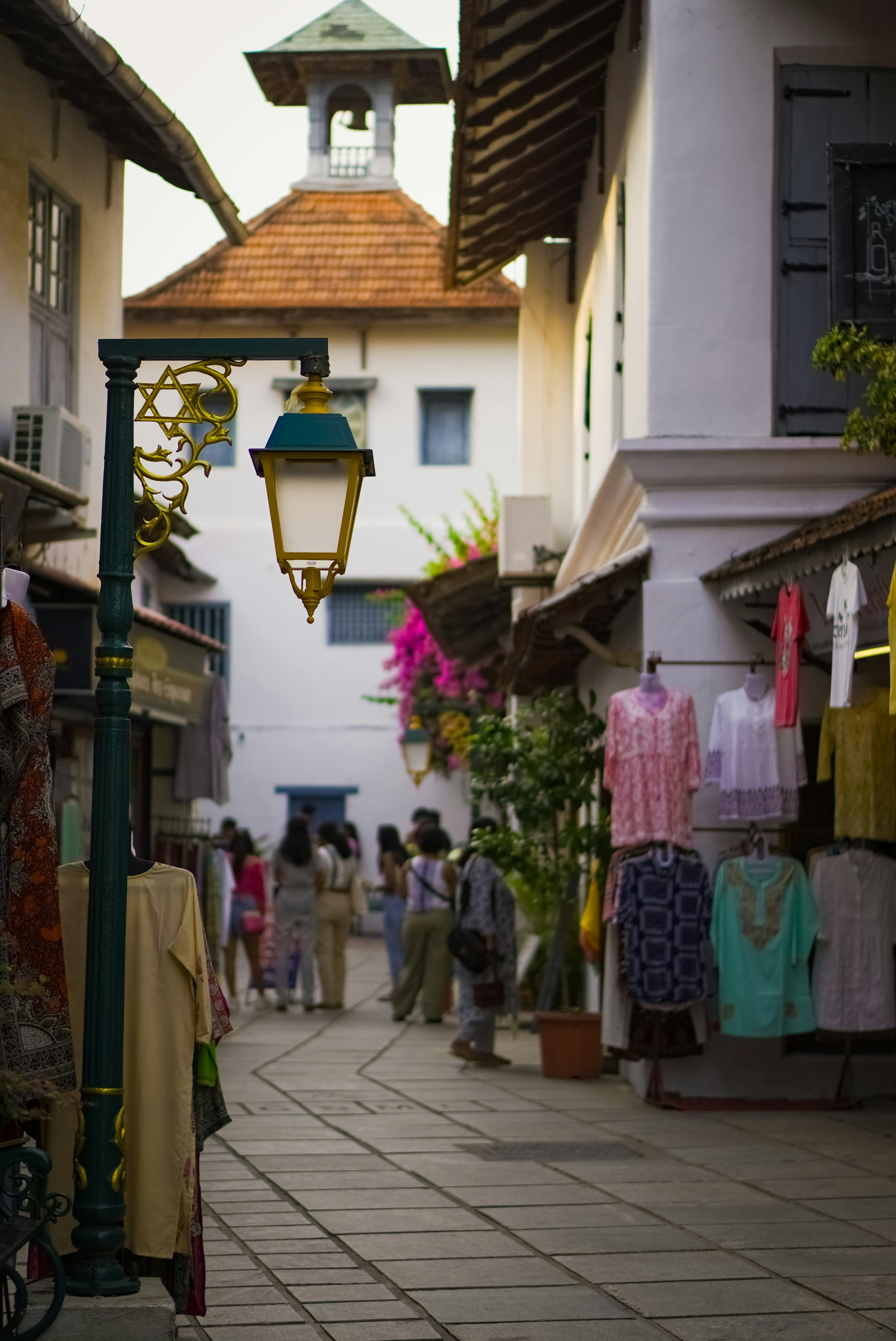 a street with people walking down it and a lamp post in the middle of the