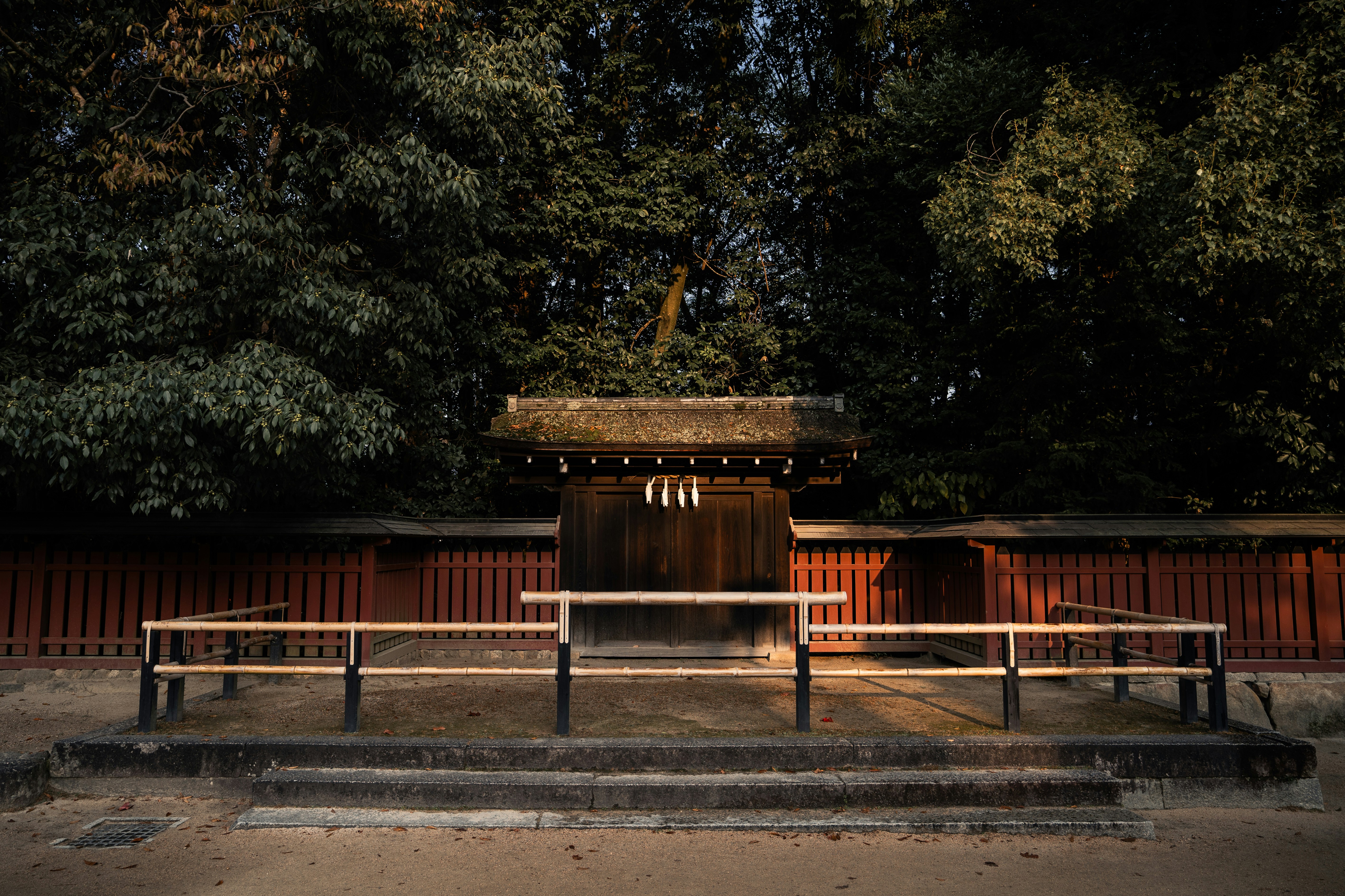 a wooden bench sitting in front of a red fence
