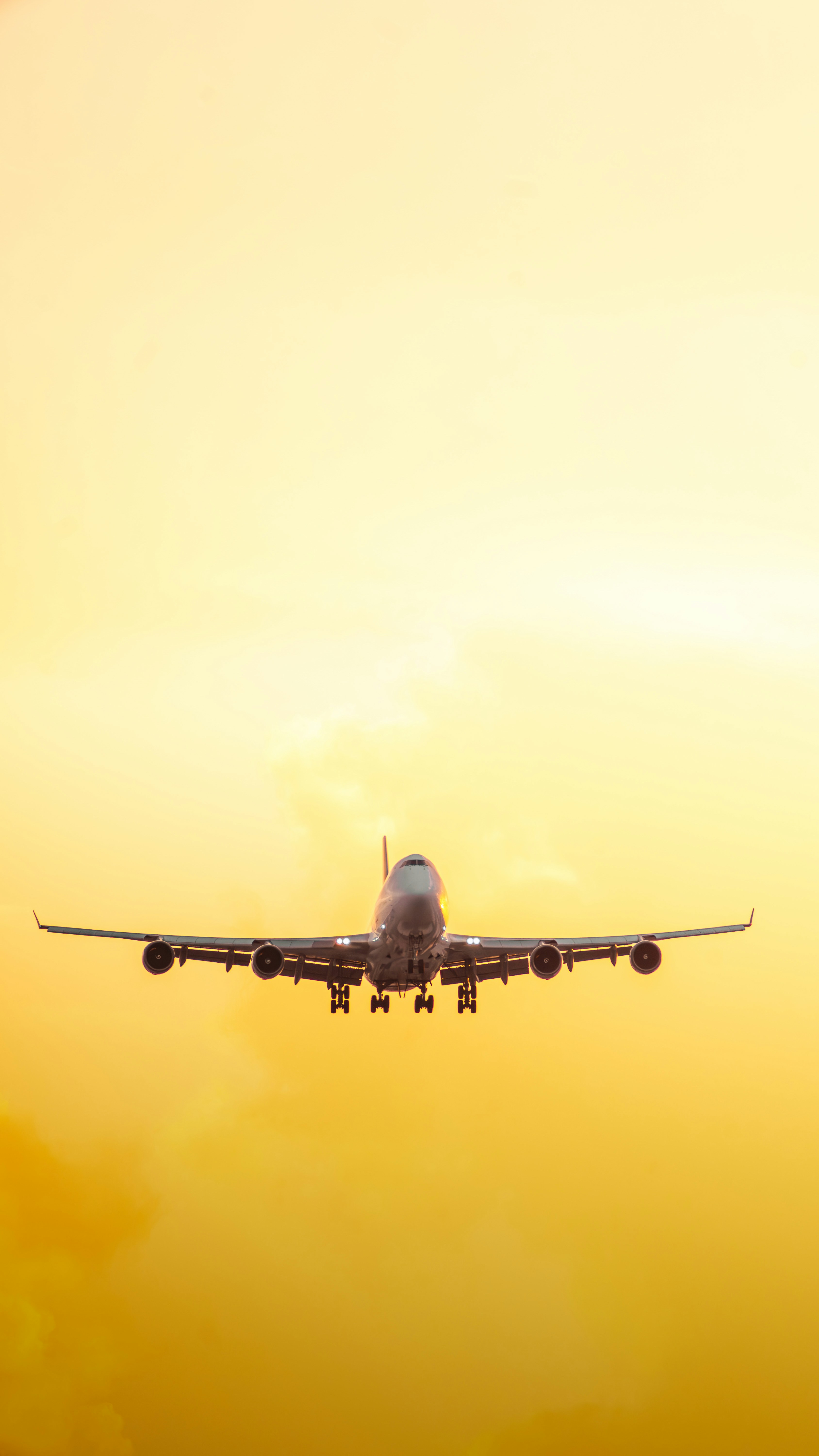 a large jetliner flying through a yellow sky