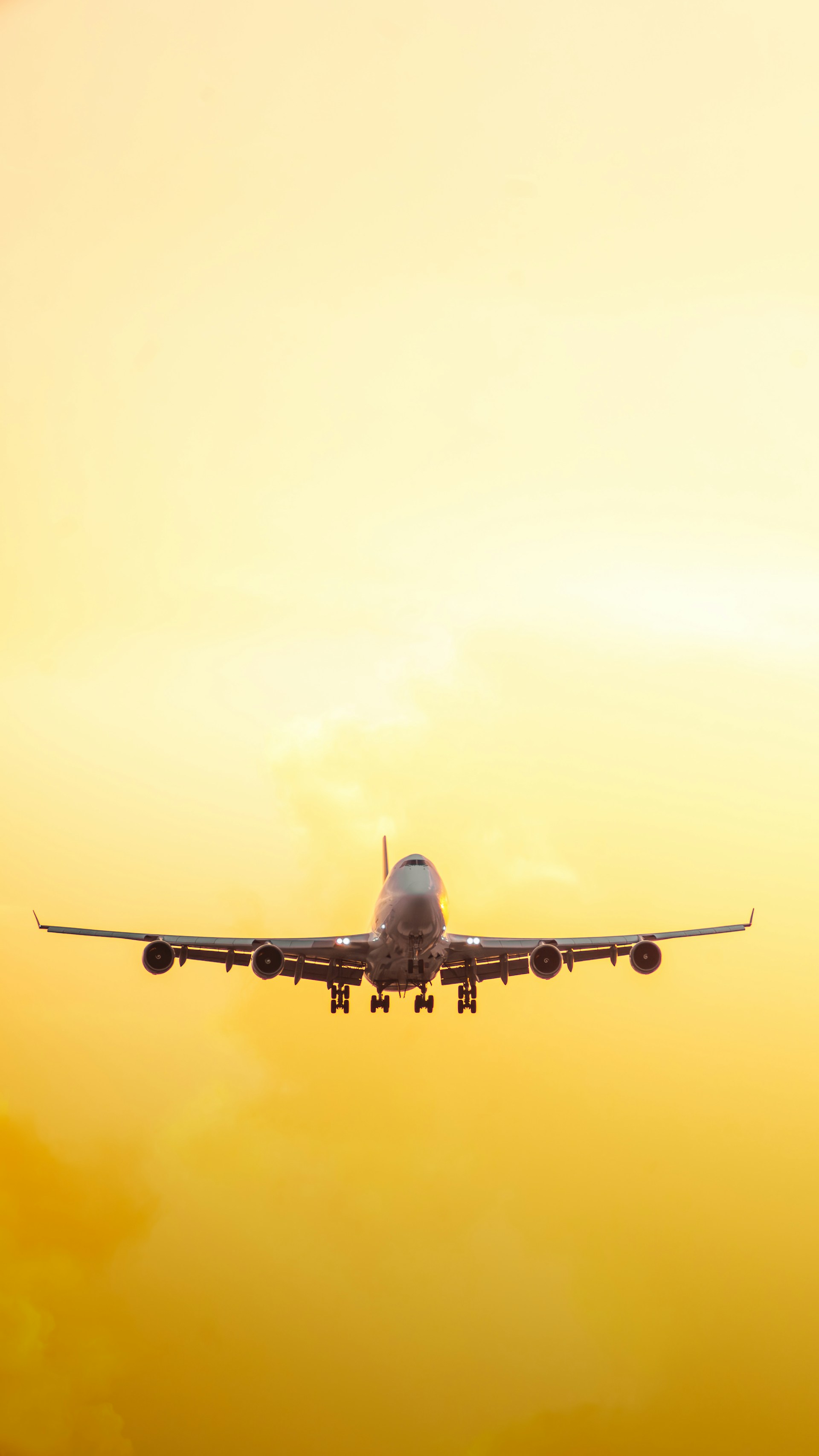 a large jetliner flying through a yellow sky