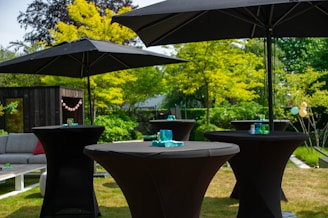 a couple of black tables sitting under umbrellas