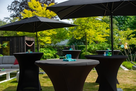 a couple of black tables sitting under umbrellas