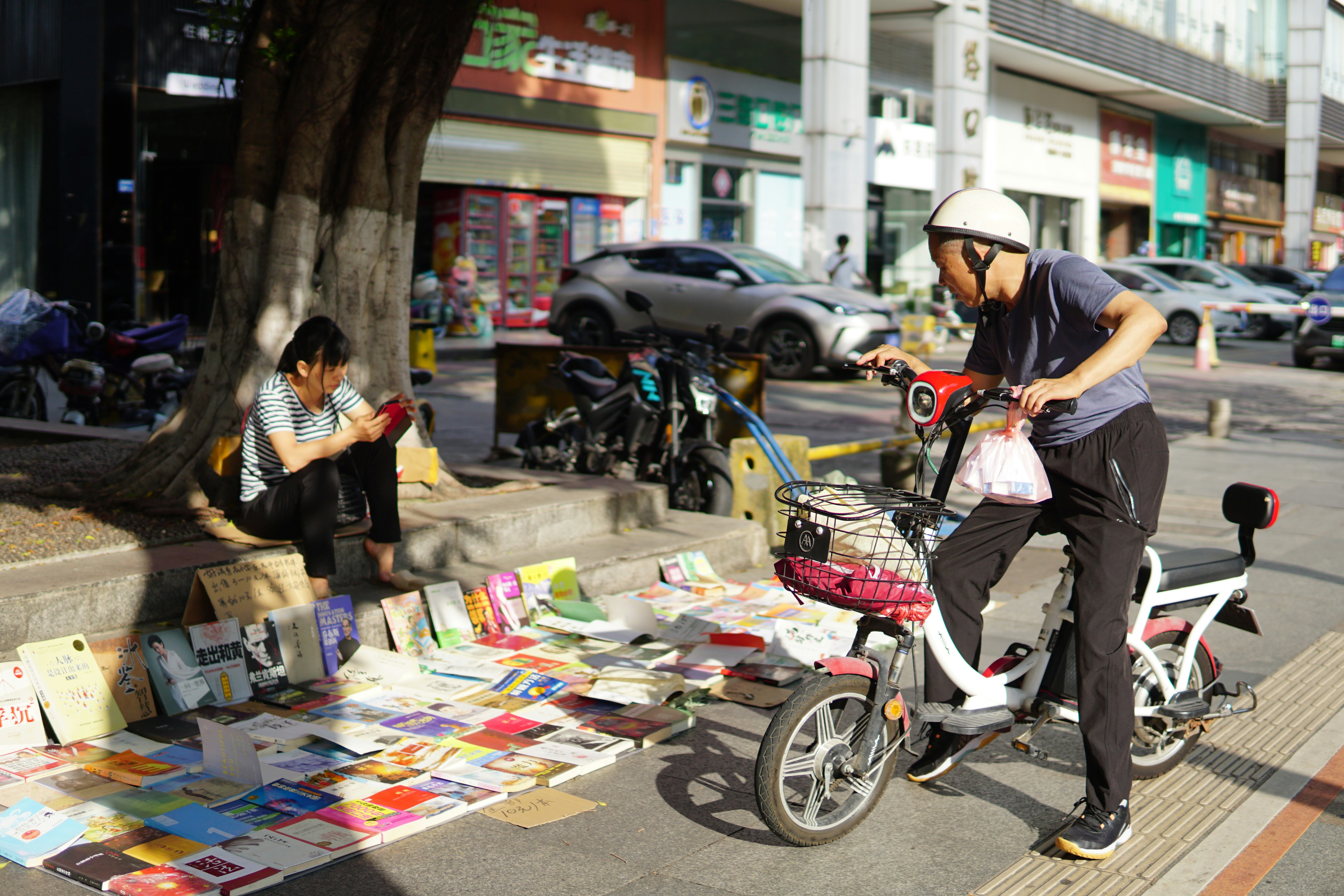 a man riding a bike down a street next to a woman