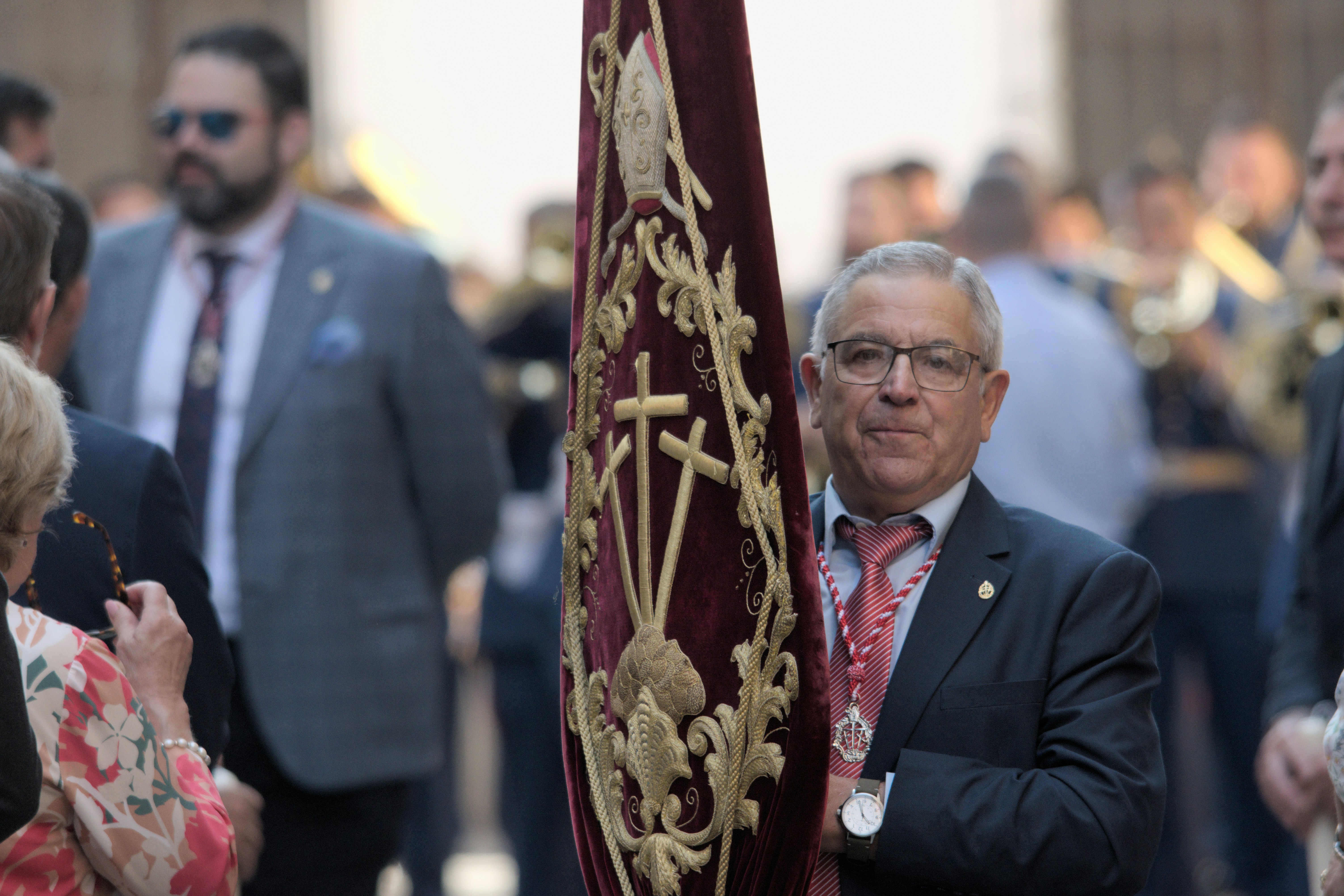 a man in a suit and tie standing next to a flag