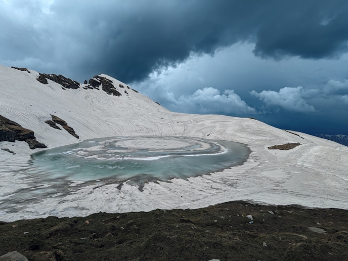 a snow covered mountain with a circular pool of water