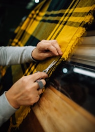 a person cutting a piece of fabric with a pair of scissors
