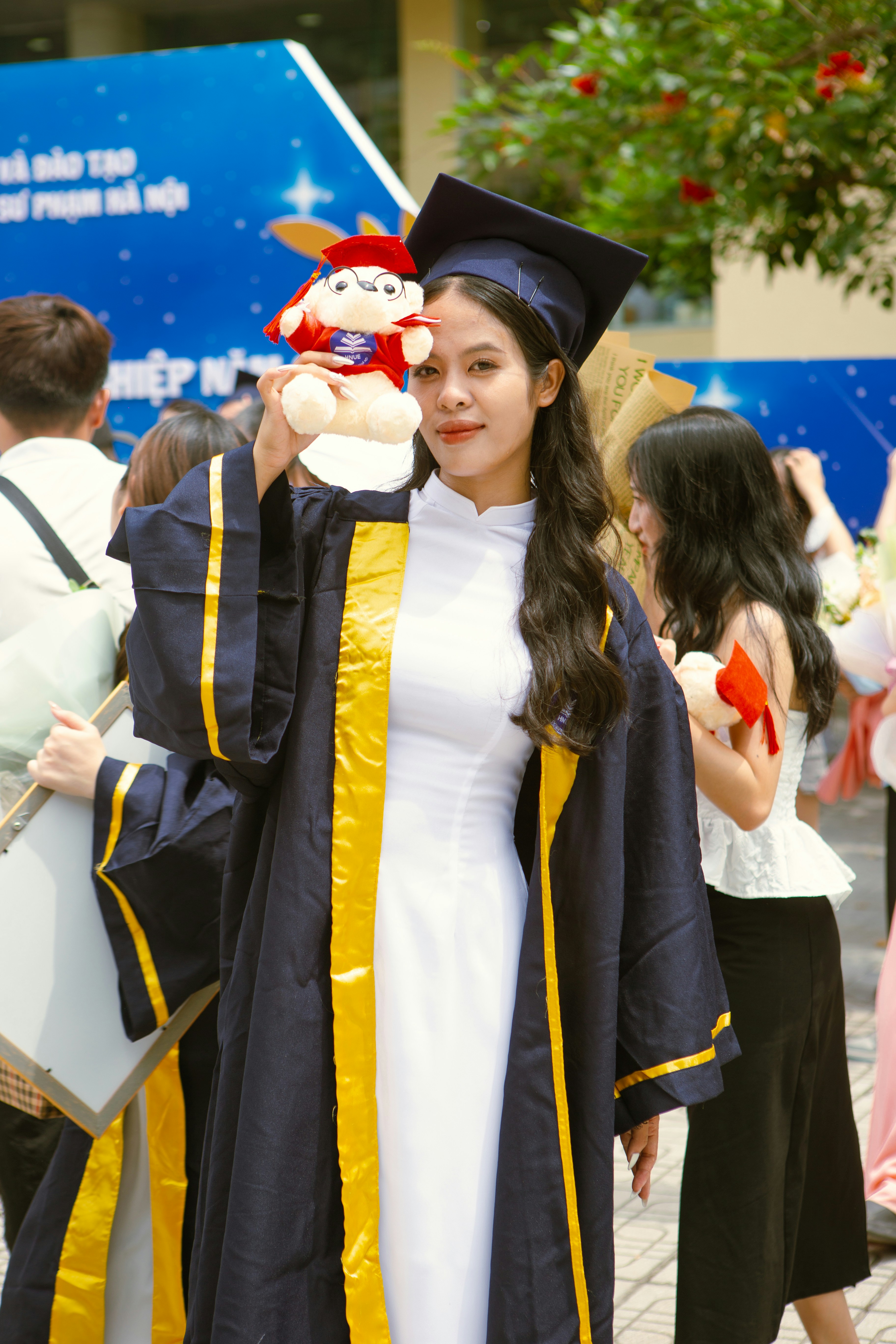 a woman in a graduation gown holding a stuffed animal