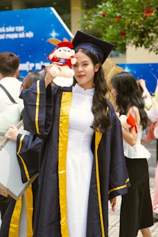 a woman in a graduation gown holding a stuffed animal