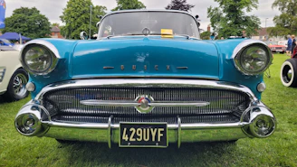 a blue classic car parked on top of a lush green field