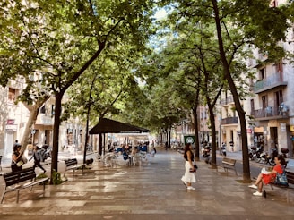 a woman is walking down a tree lined street