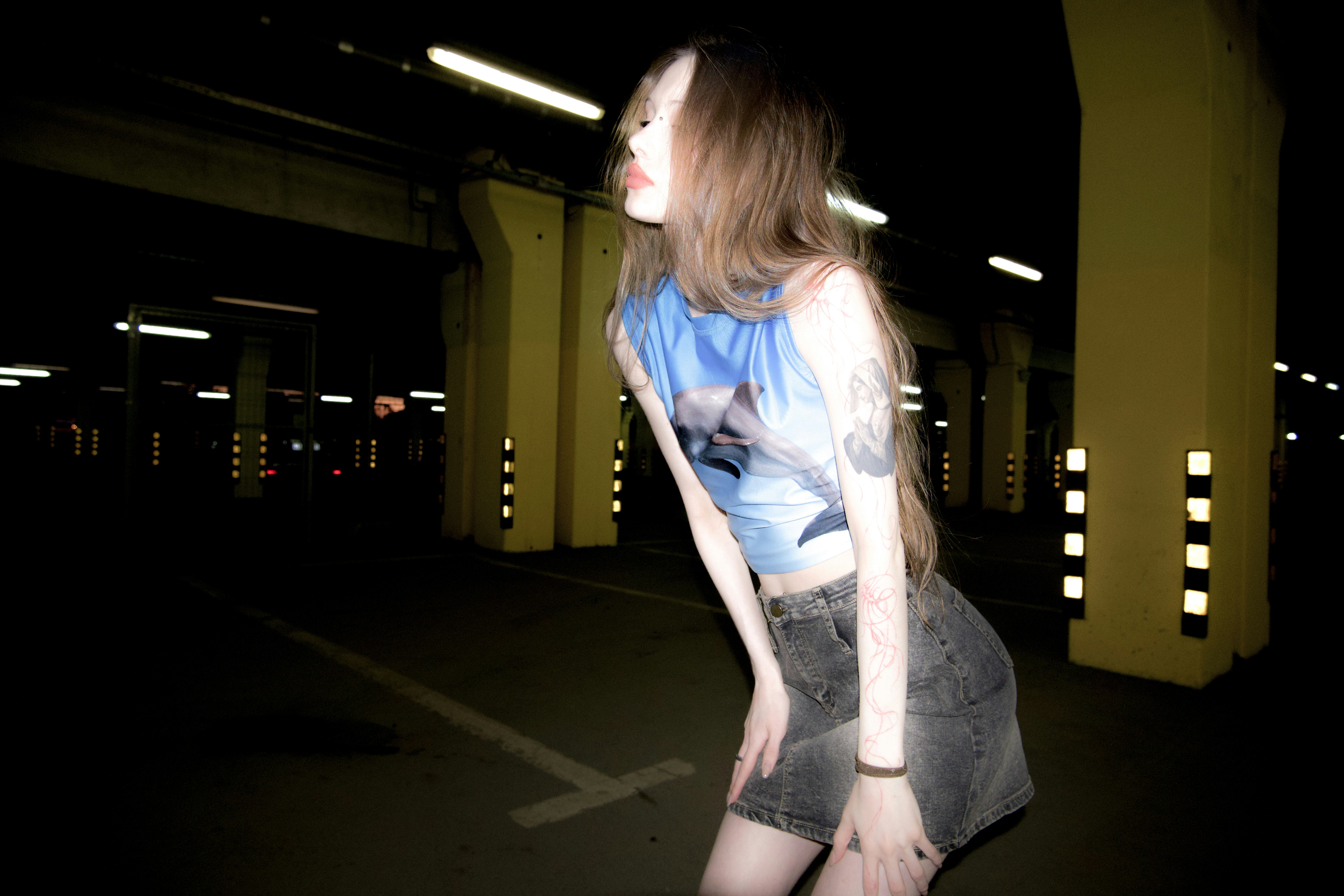 a woman in a blue shirt is standing in a parking lot