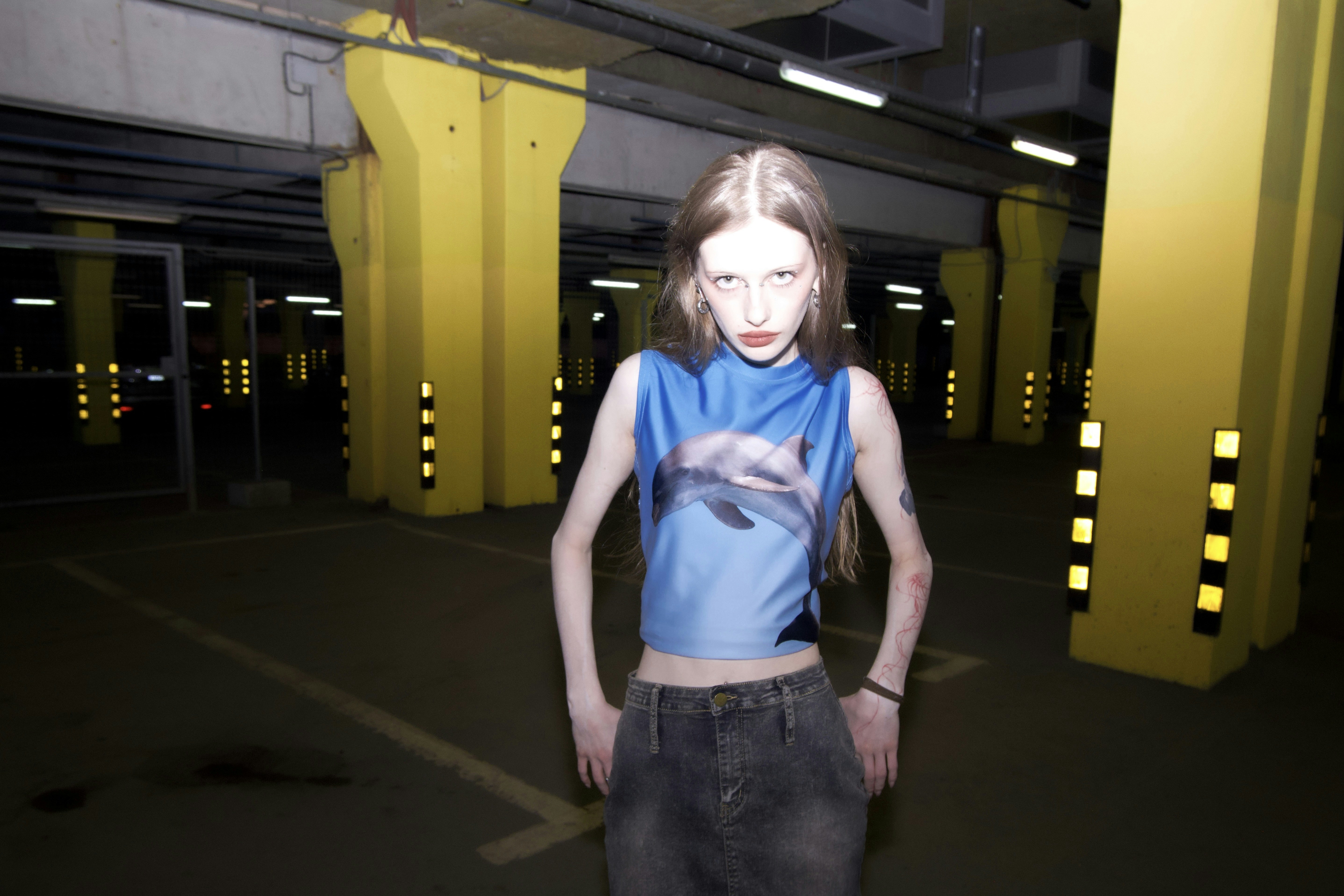 a woman in a blue shirt standing in a parking garage