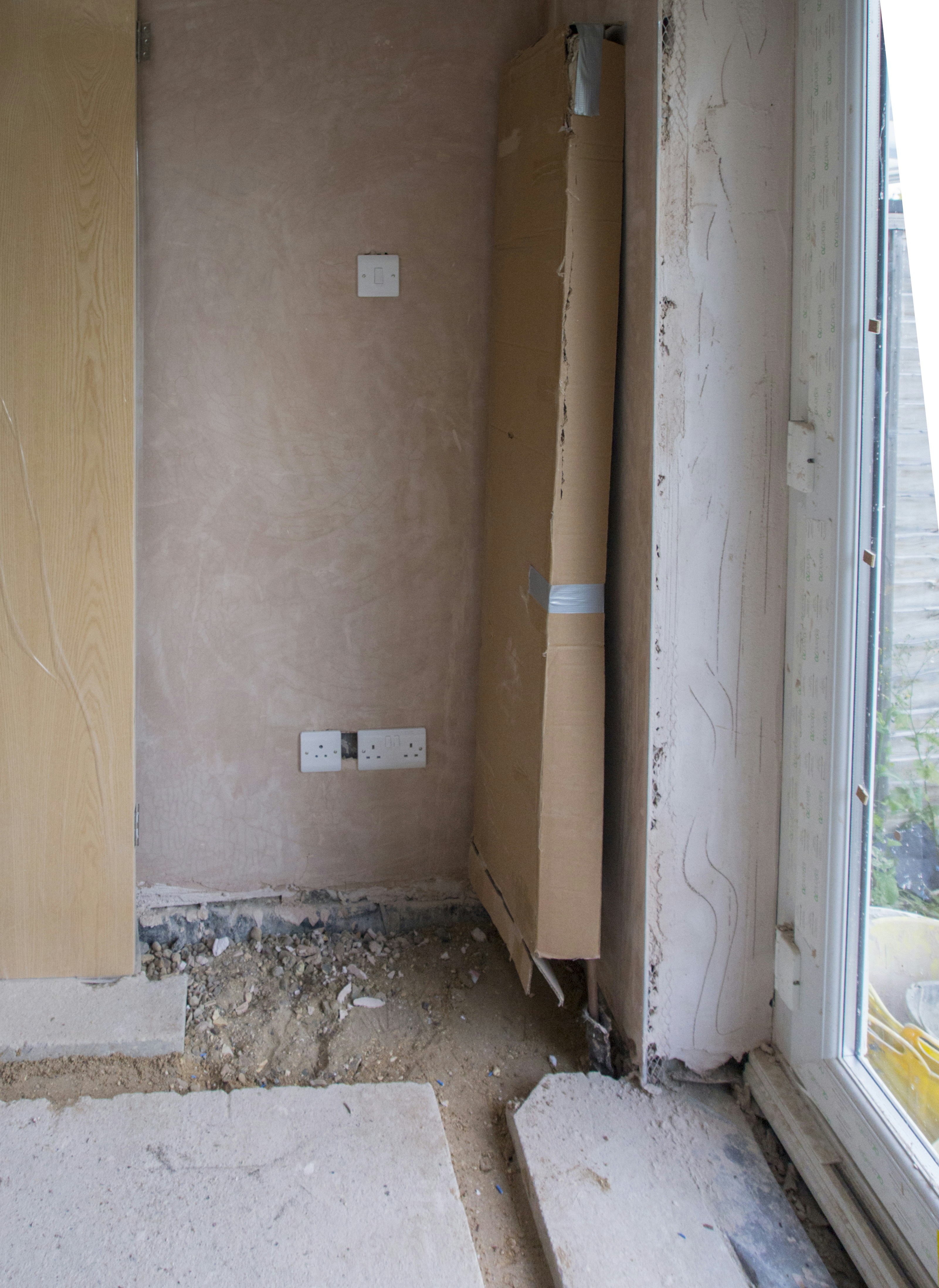 Frustrated homeowner looking at unfinished renovation work with exposed walls and construction debris