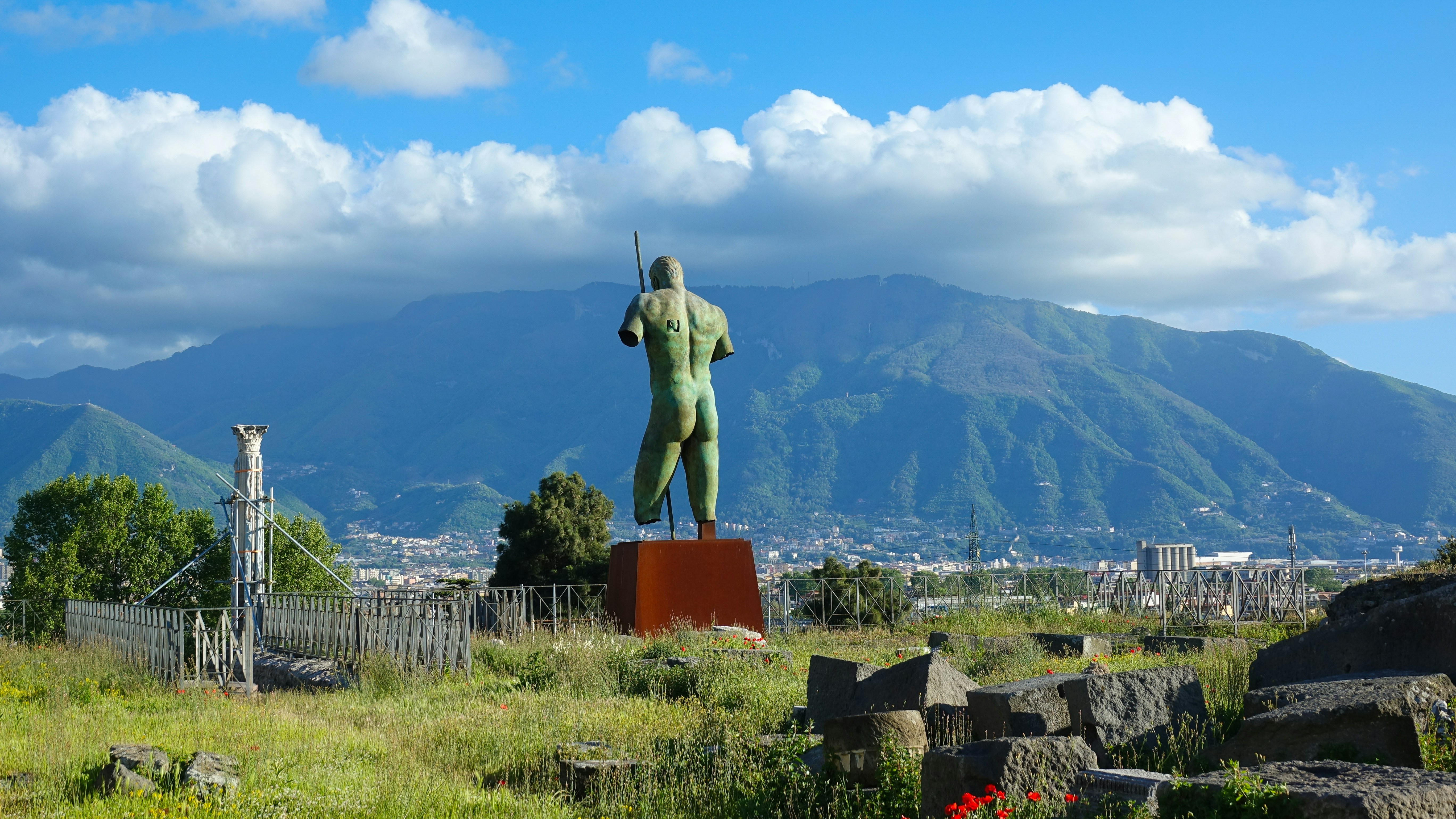 a statue of a man in a field with mountains in the background