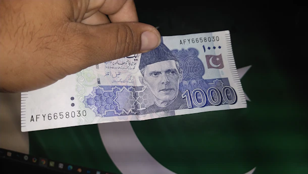 a hand holding a pakistan 100 ru note