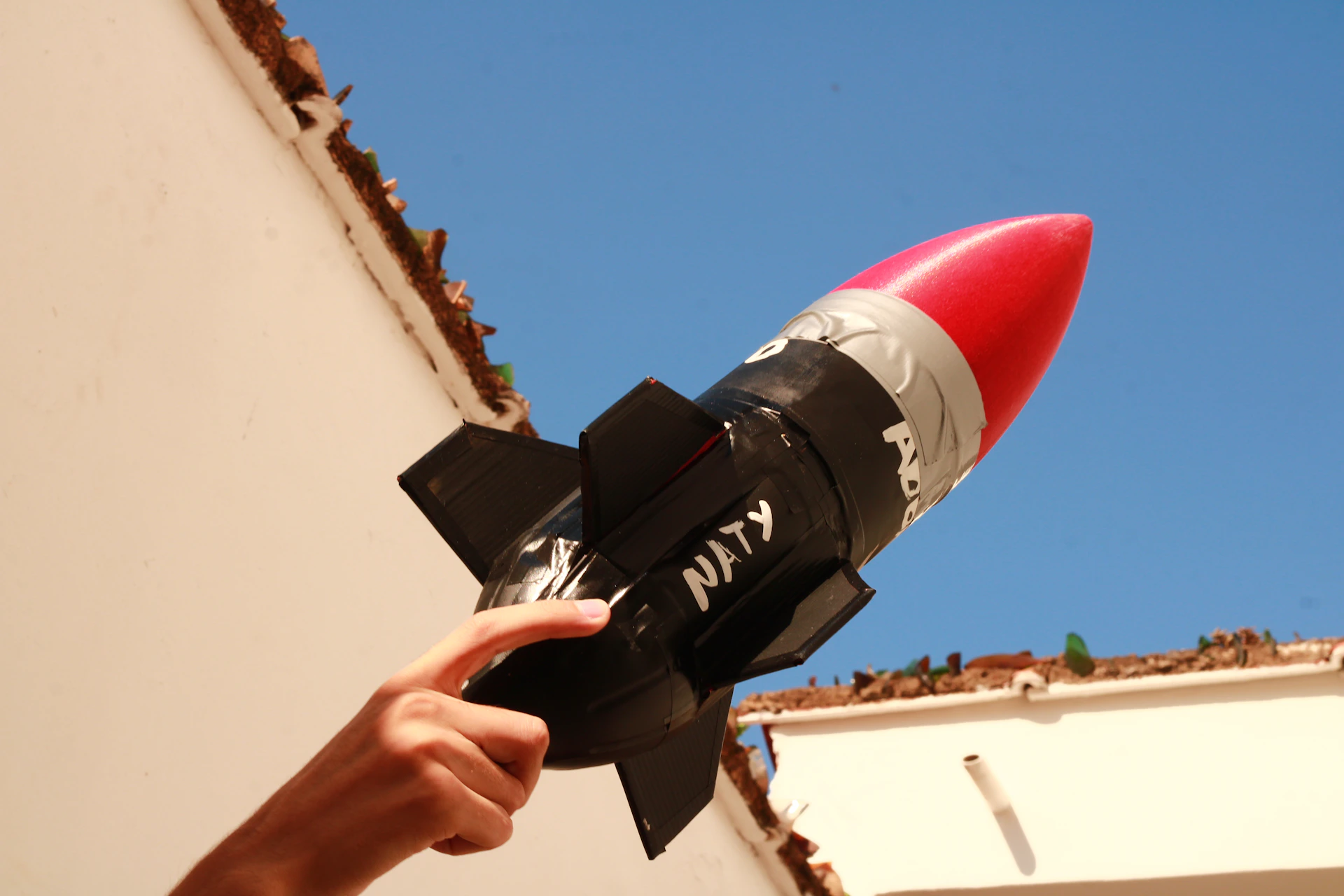 a hand is holding a model of a rocket ship