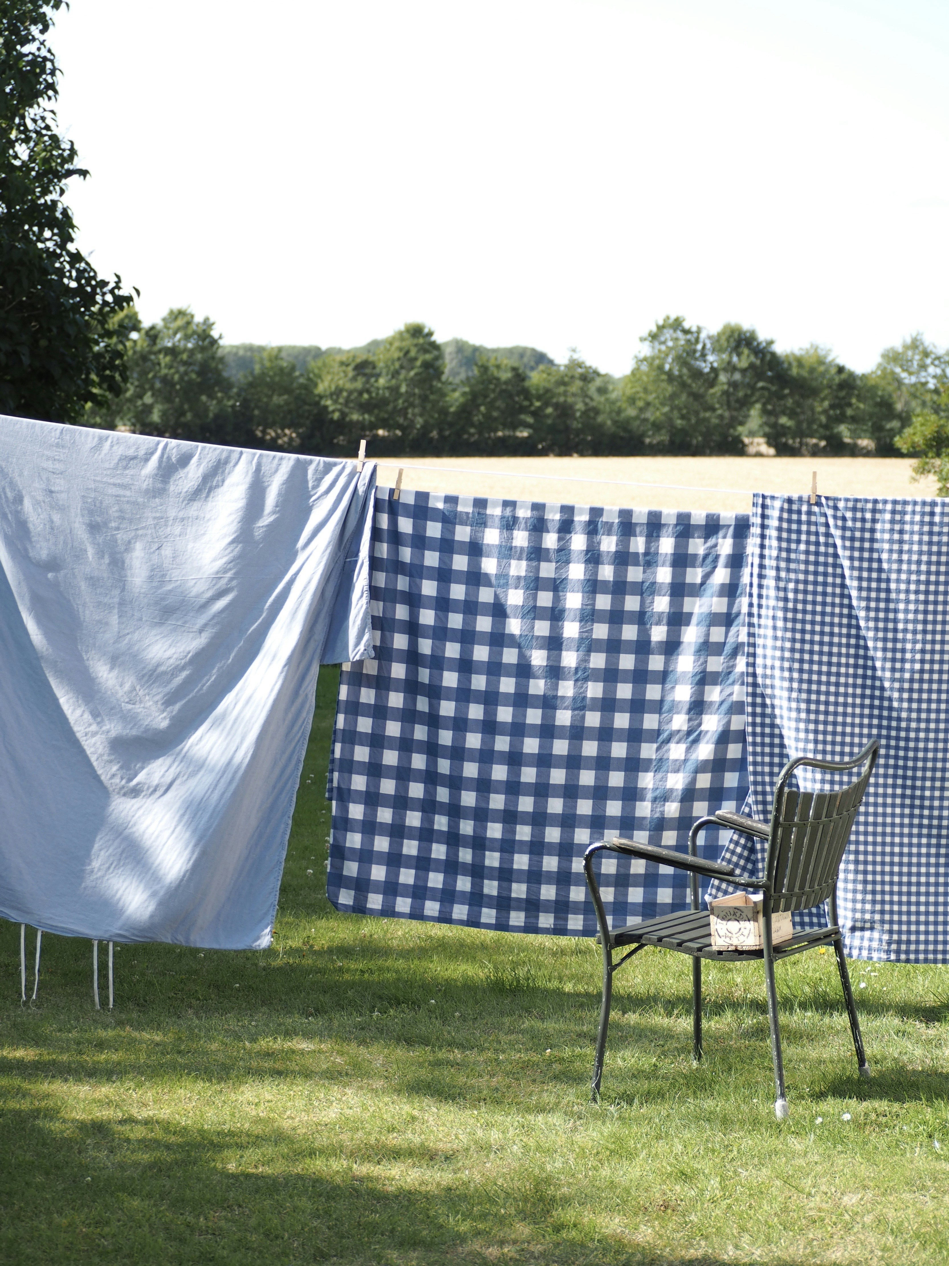 a lawn chair sitting in the grass next to a blue and white checkered cloth