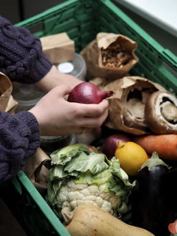a person holding an apple in front of a pile of vegetables
