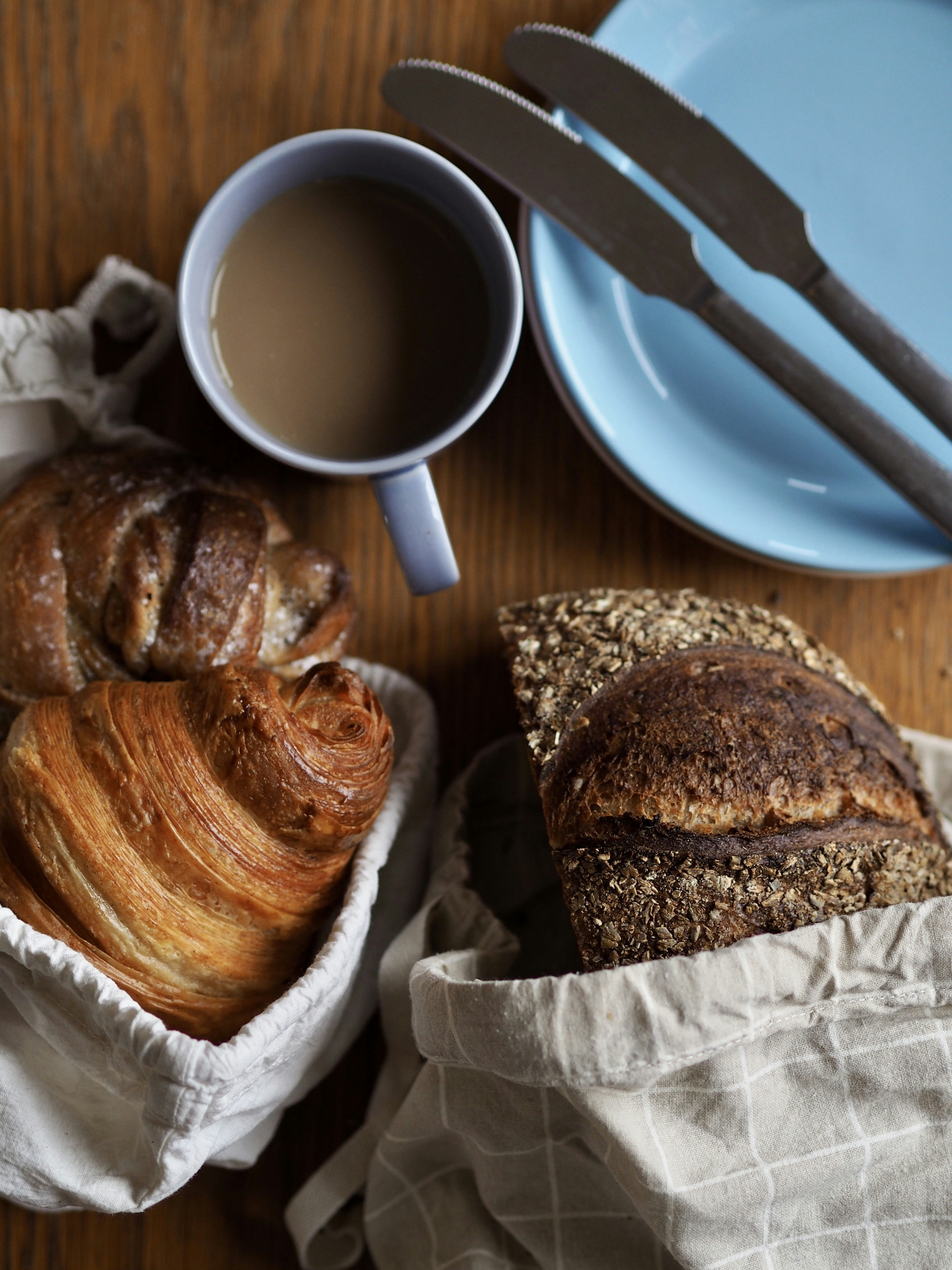 a wooden table topped with bread and a cup of coffee
