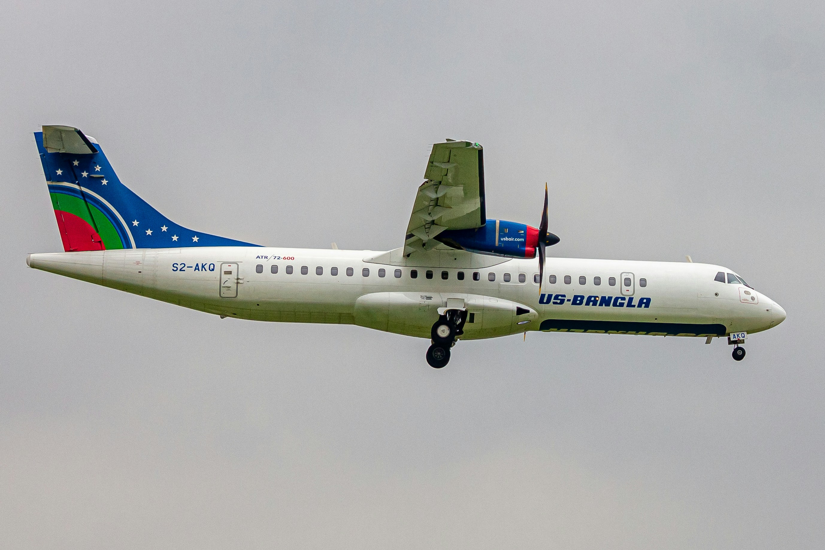 a large passenger jet flying through a cloudy sky, US BANGLA S2-AKQ