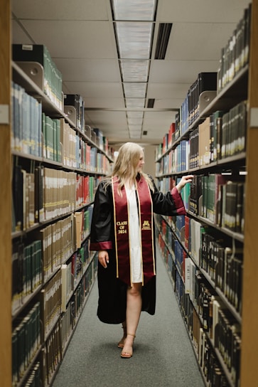a woman in a graduation gown is walking through a library