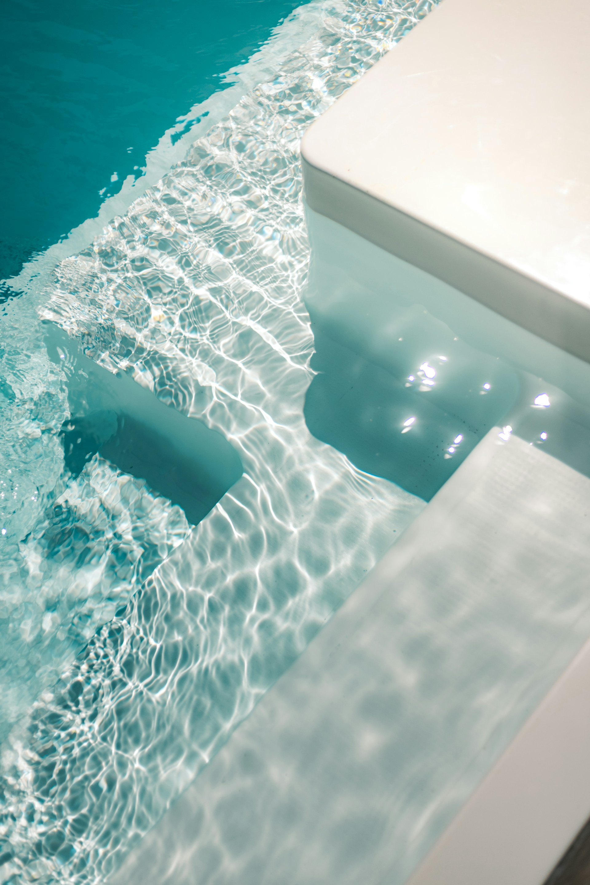 a pool with clear blue water and a white bench
