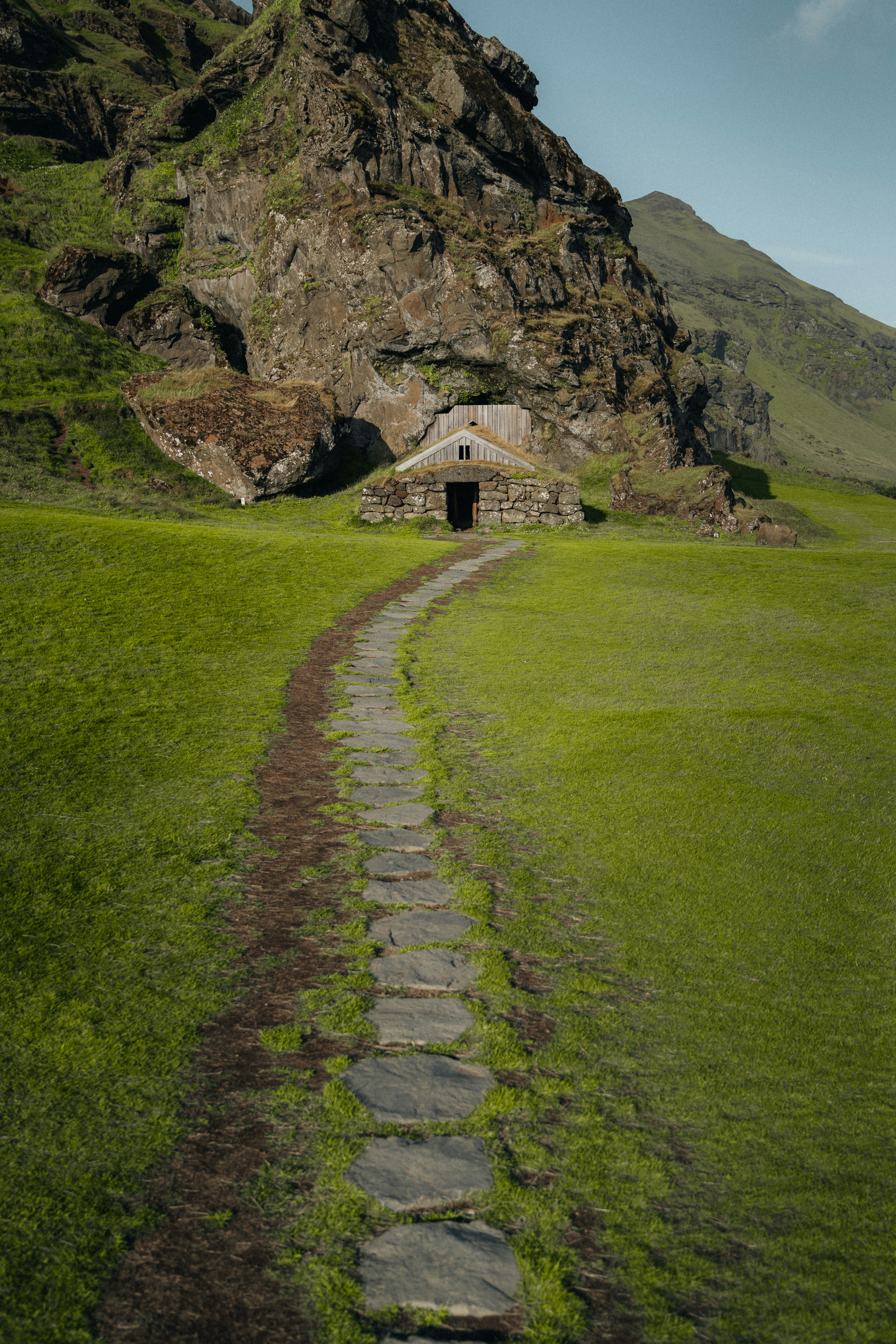 a stone path leading to a small hut in the mountains