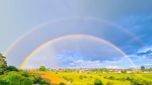 two rainbows in the sky over a green field